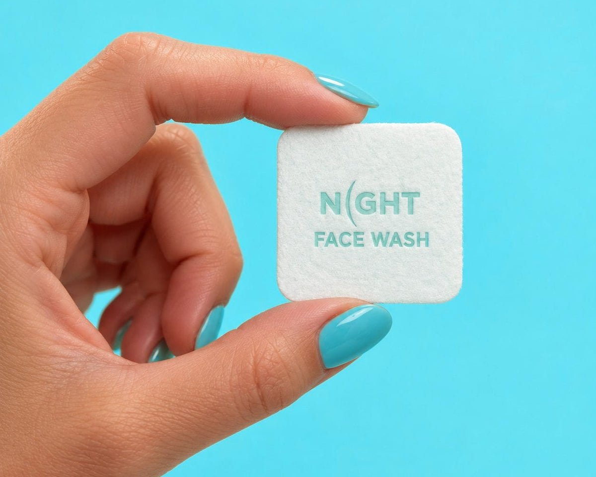 A hand holding one NIGHT face wash square.