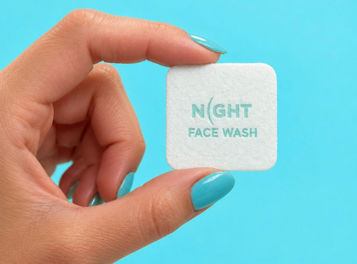A hand holding one NIGHT face wash square.