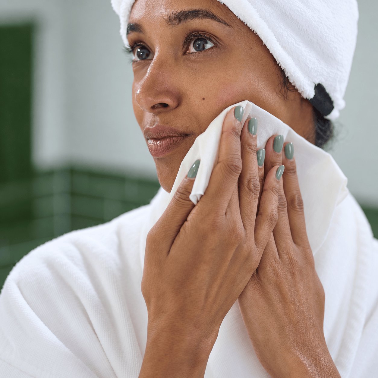 A woman gently cleansing her cheek with a NIGHT raw silk washcloth.
