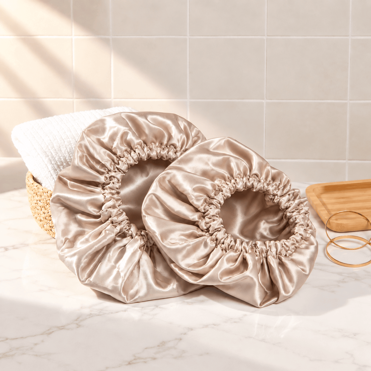 Two Champagne shower caps with gathered elastic edges on a marble vanity