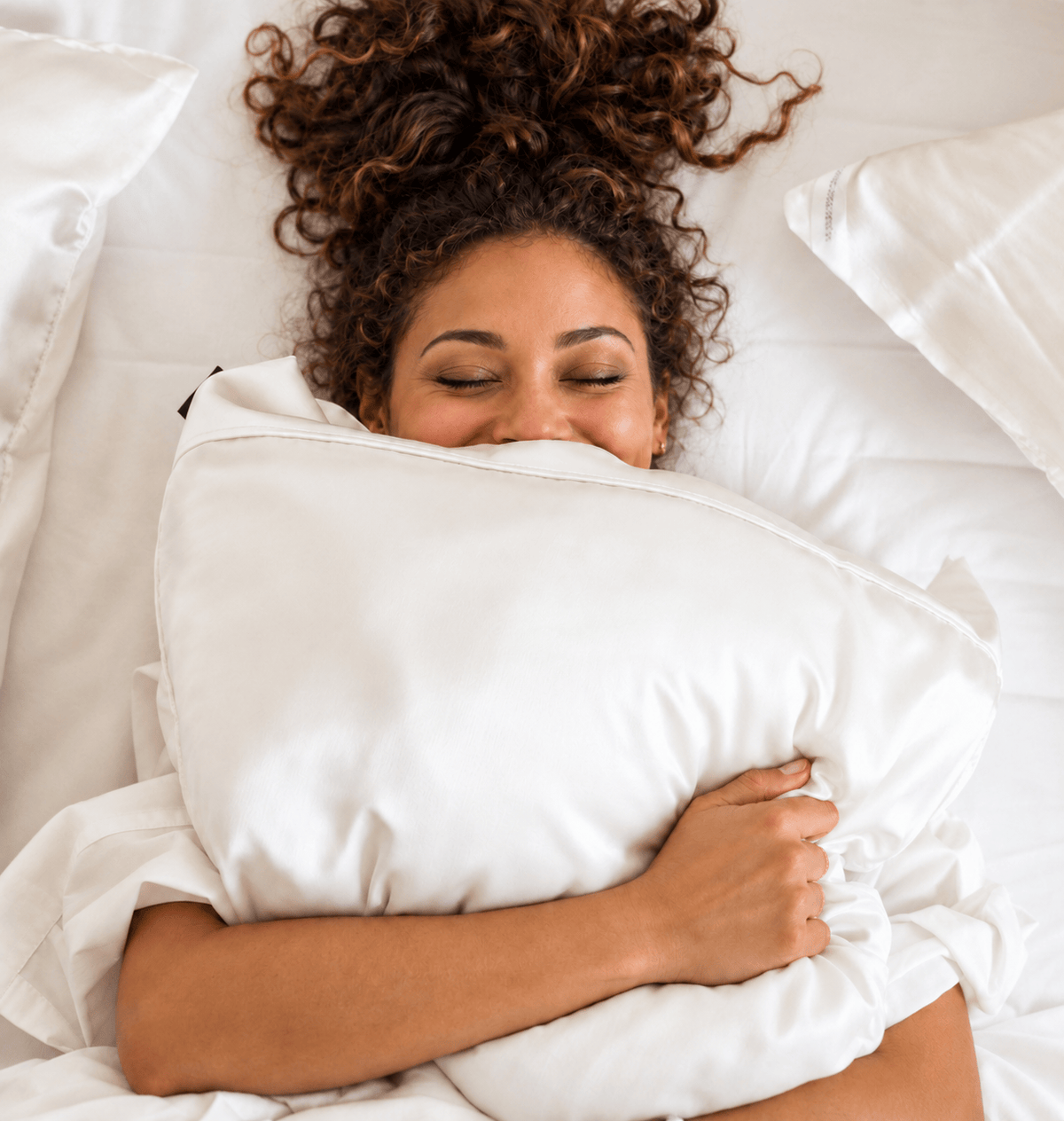 Woman resting with her eyes closed and hugging a white DualSilk pillowcase