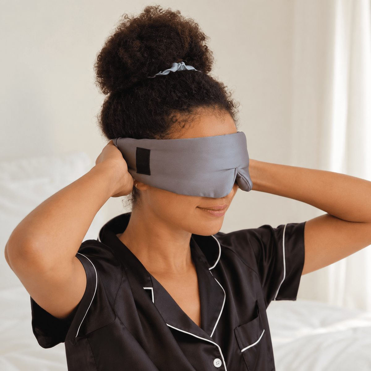 Model wearing the gunmetal silk sleep mask with black pajamas