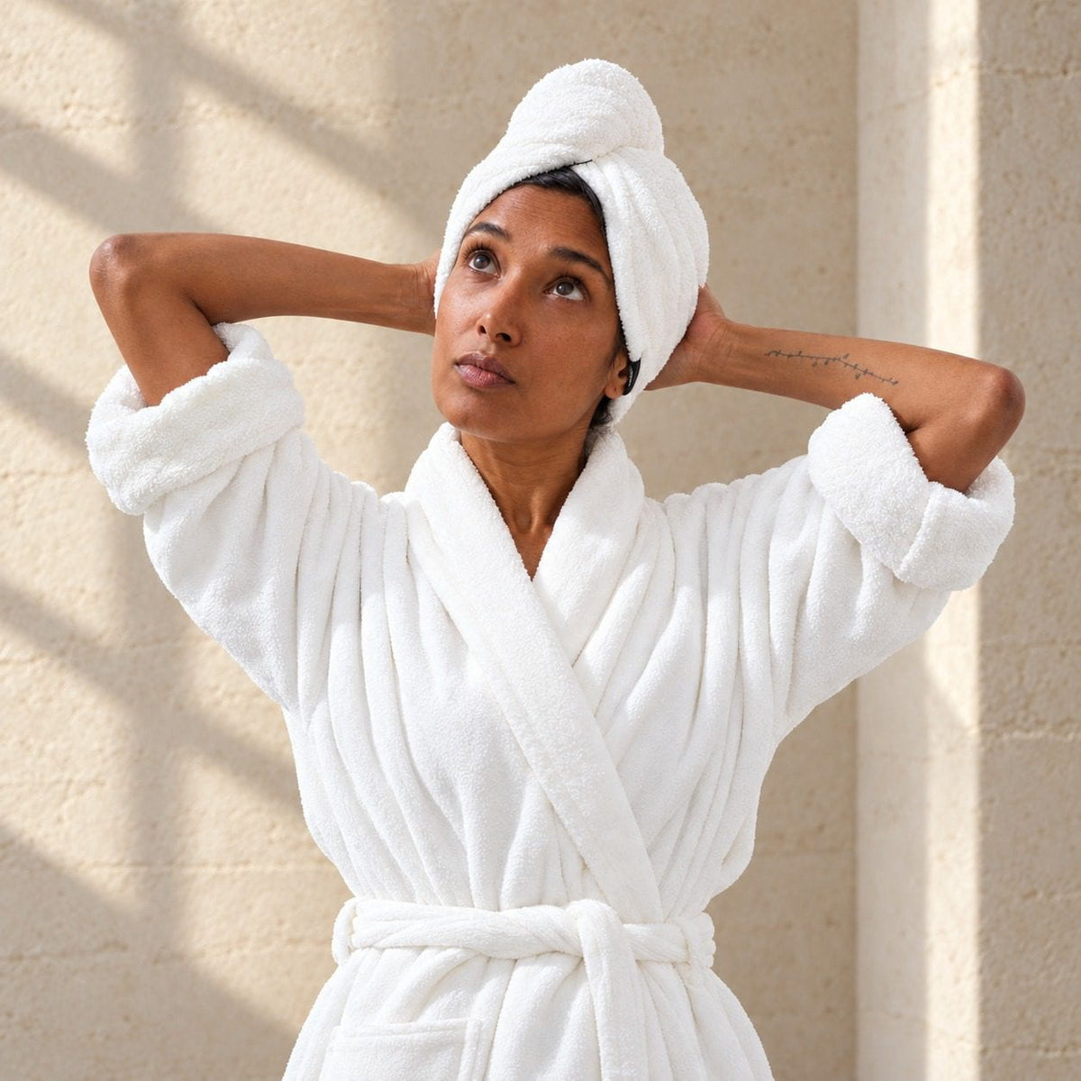 Woman wearing the NIGHT Quick Dry Hair Towel in Spa White, with hands behind her head.