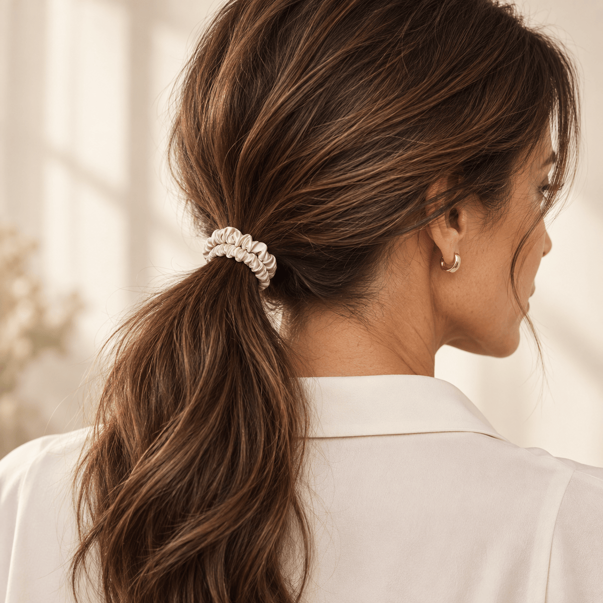 Champagne skinny silk scrunchie securing a low ponytail