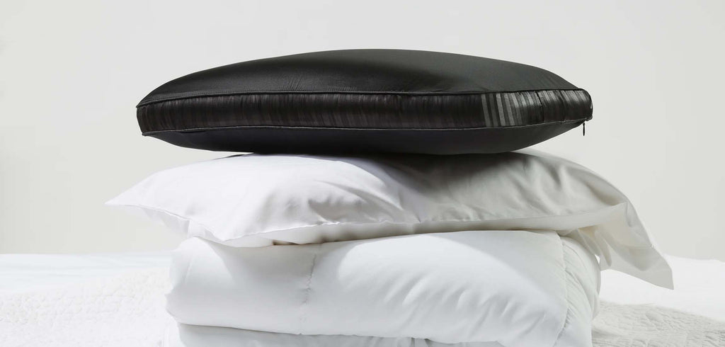 Famous black NIGHT silk pillow sitting on top of stack of white pillows