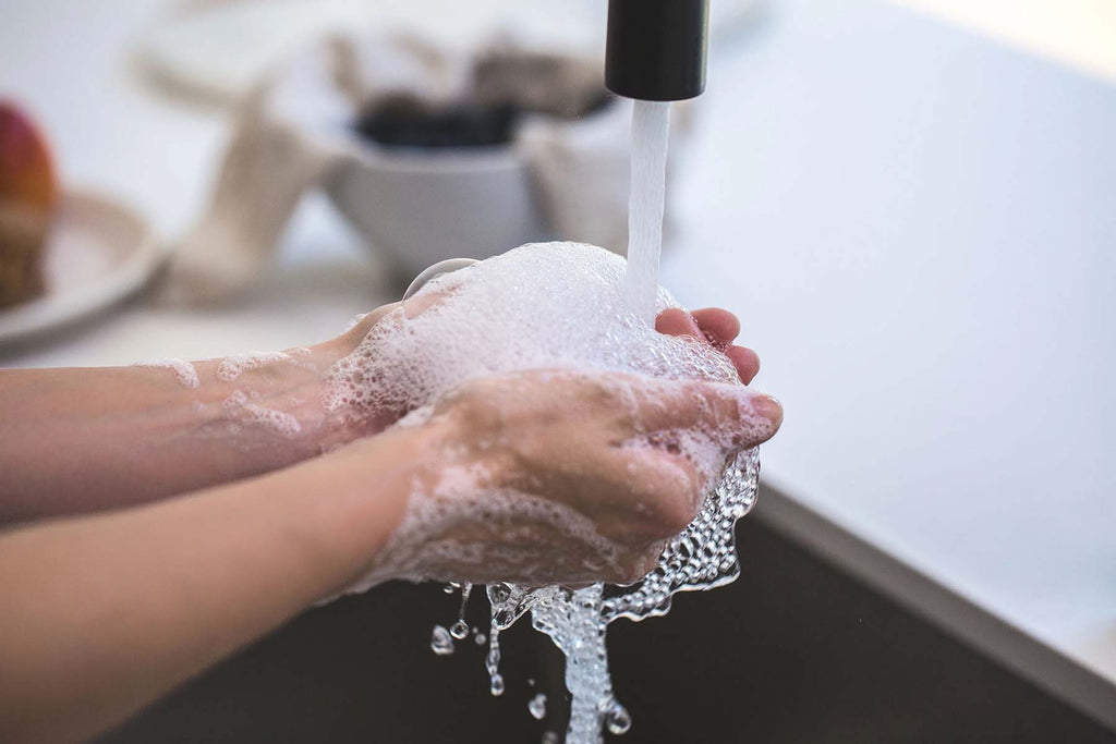 Soapy hands rinsing in water in sink