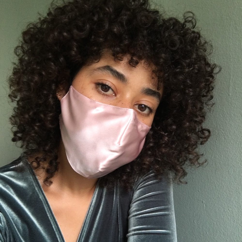 woman with curly hair wearing blush satin mask
